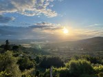 A panoramic photograph of a lush, green Tuscan valley at sunset, serving as the featured image and link to all posts from the Tuscany journey. The hills and forests are bathed in a warm, golden light, capturing the serene and picturesque beauty of the Italian countryside.